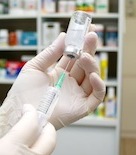 clinical trial represented by gloved hands filling syringe 