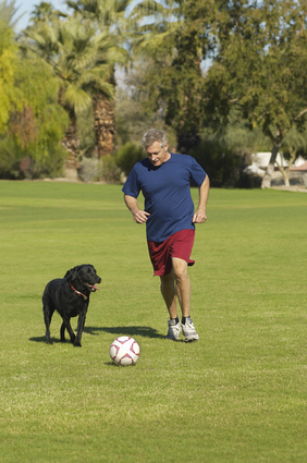 Man playing soccer with his dog
